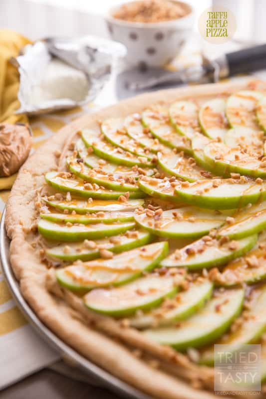 Taffy Apple Pizza // When you start with a sugar cookie crust, it's hard to go wrong. Add on a creamy layer of peanut butter and cream cheese. Top with sliced apples, caramel, and chopped nuts. This Taffy Apple Pizza will be the star of the party! | Tried and Tasty