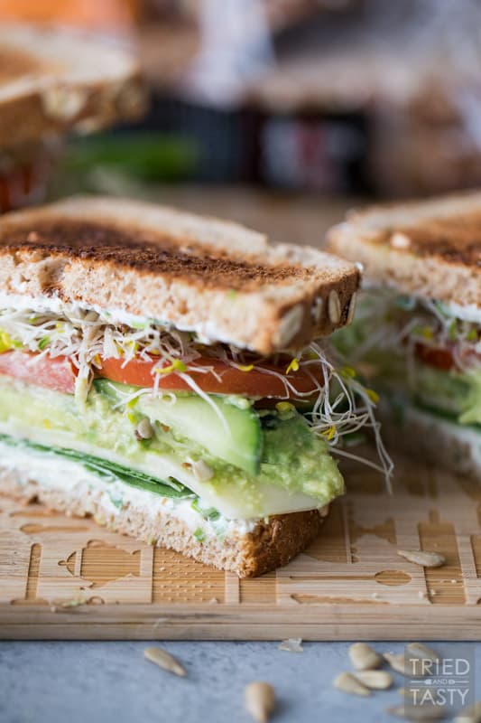 A close up photo of a Veggie Sandwich sliced in half on a wooden cutting board