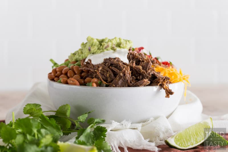 Barbacoa Beef Burrito Bowl with cheese, salsa, corn, lettuce, pinto beans, gaucamole, lime, cilantro & sour cream on top.