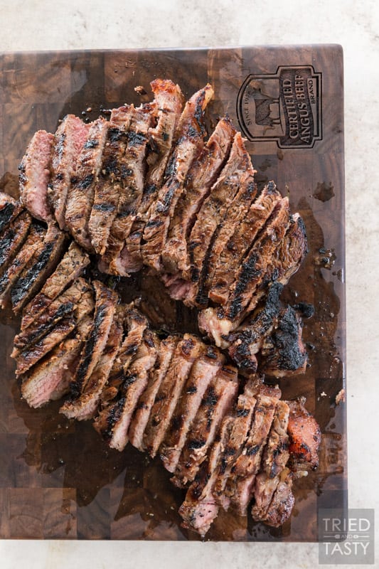 Grilled steaks after being sliced on a cutting board.